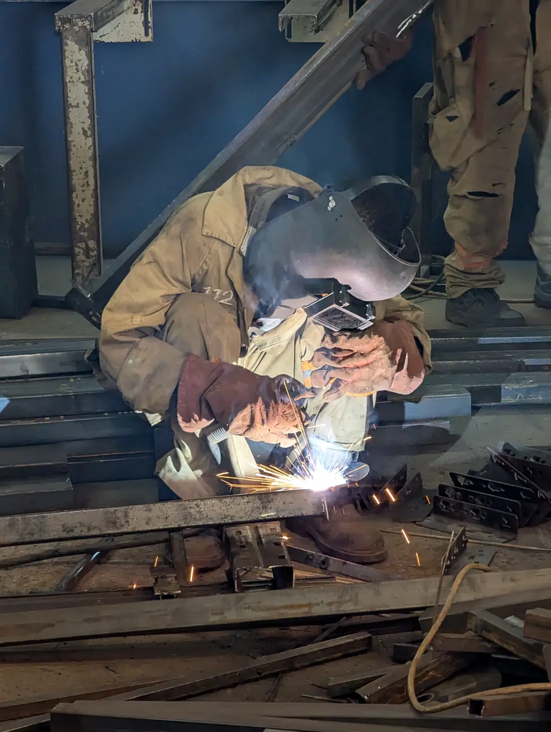 Fabbro che salda profilati in acciaio in officina