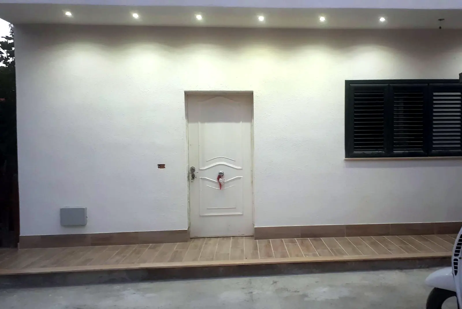 Facciata intonacata e tinteggiata di una casa, con faretti sotto la gronda