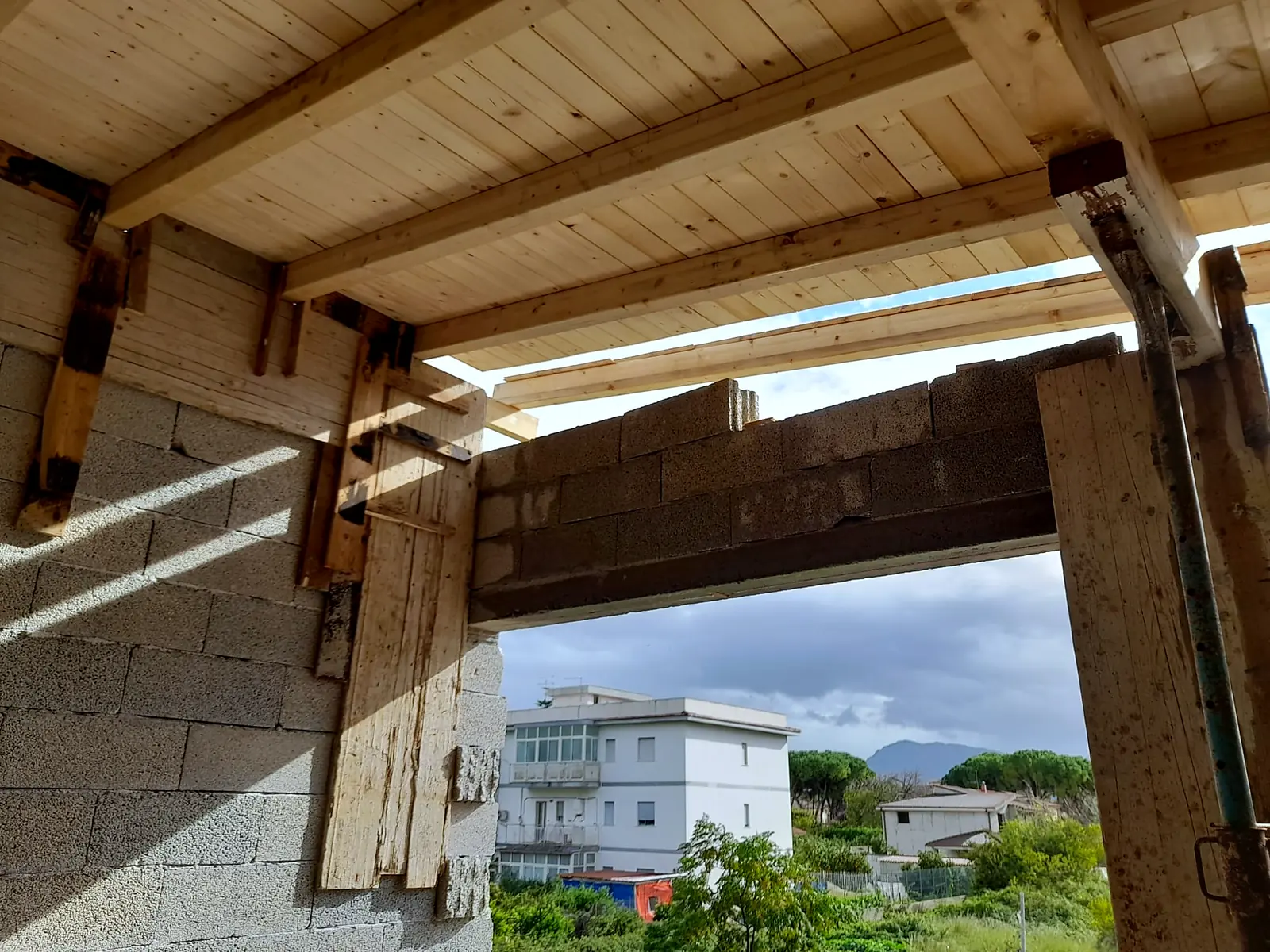 Travi in legno della copertura di un portico, con vista sulla campagna