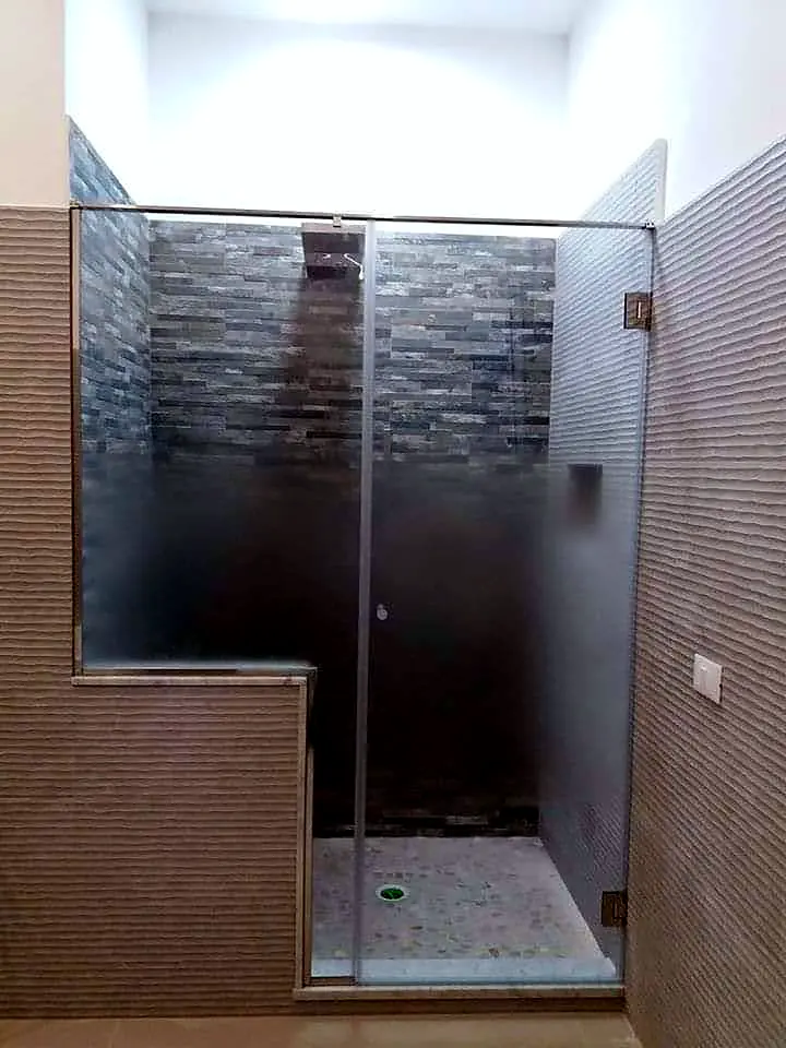 Doccia in muratura con parete a mosaico e porta in cristallo satinato
