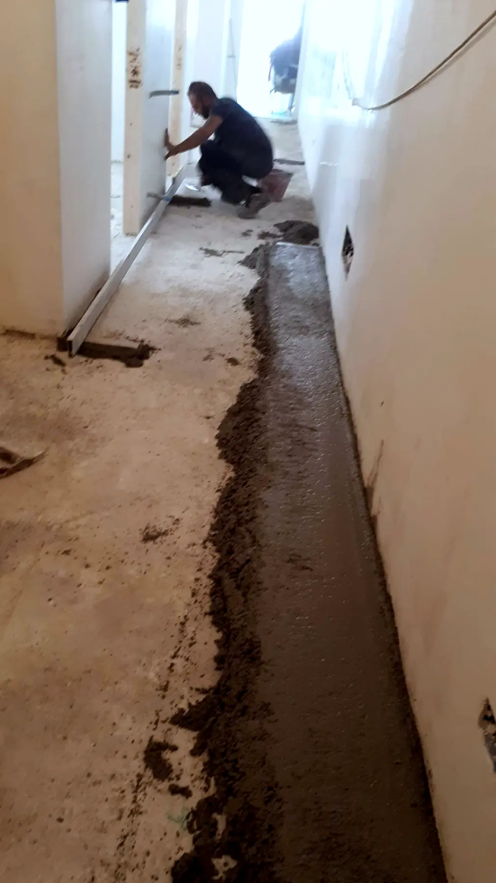 Preparazione del massetto lungo la parete, prima della posa