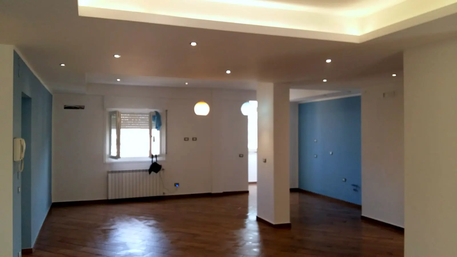 Open space ristrutturato con lampade a sospensione e pareti azzurre