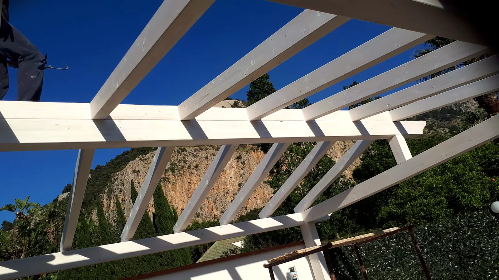Copertura a travetti di una pergola in legno bianco vista dal basso