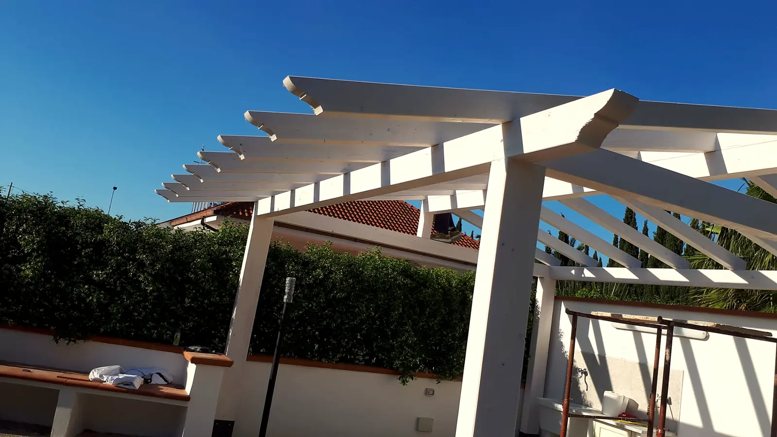 Travi e travetti di una pergola in legno bianco su un terrazzo