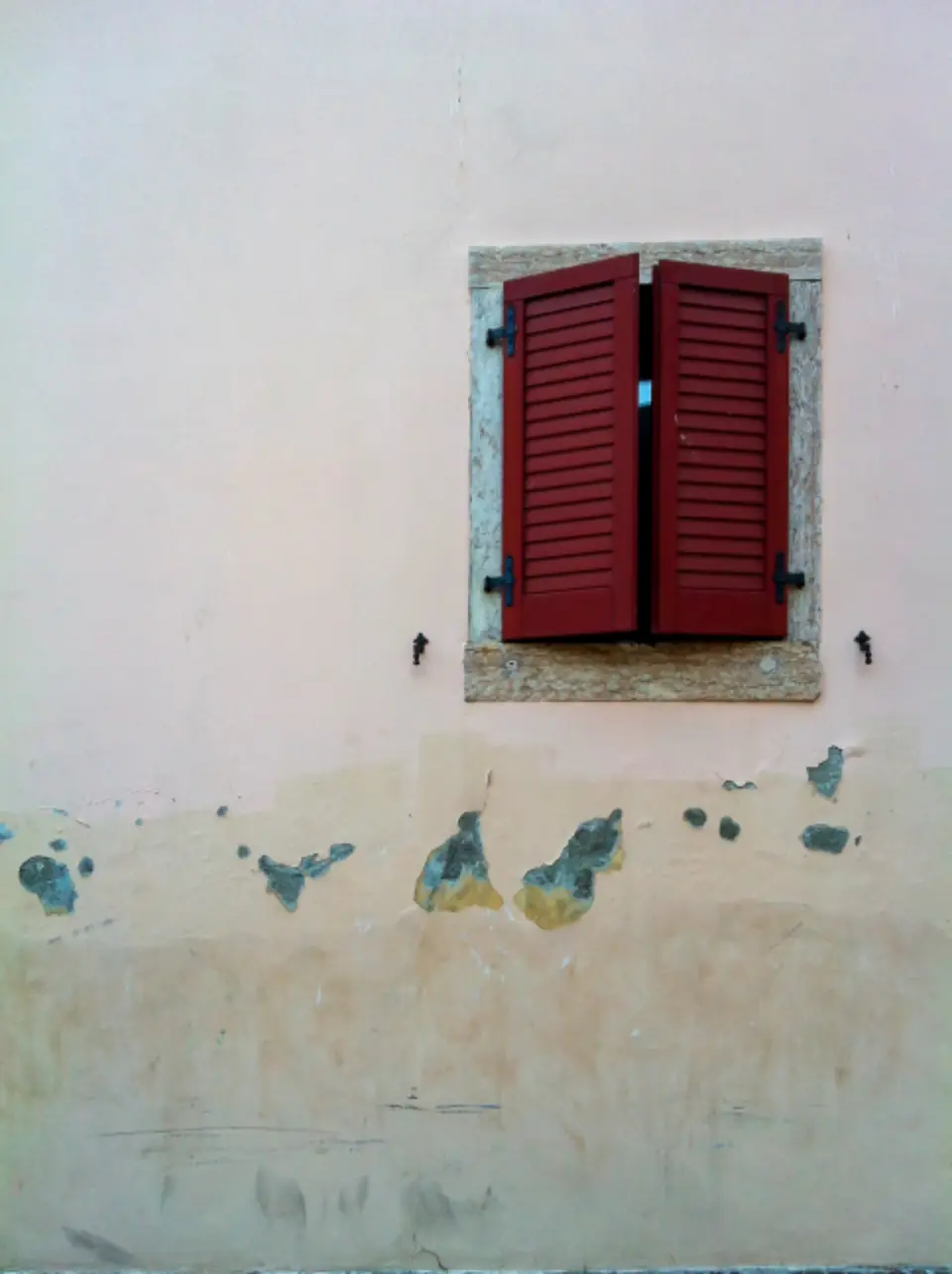 Persiane rosse su un muro antico da restaurare