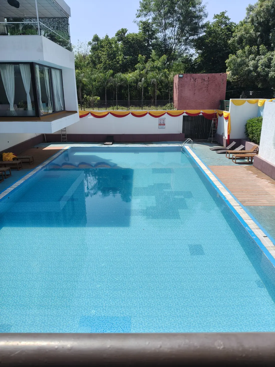 Piscina interrata rettangolare con acqua azzurra in un giardino
