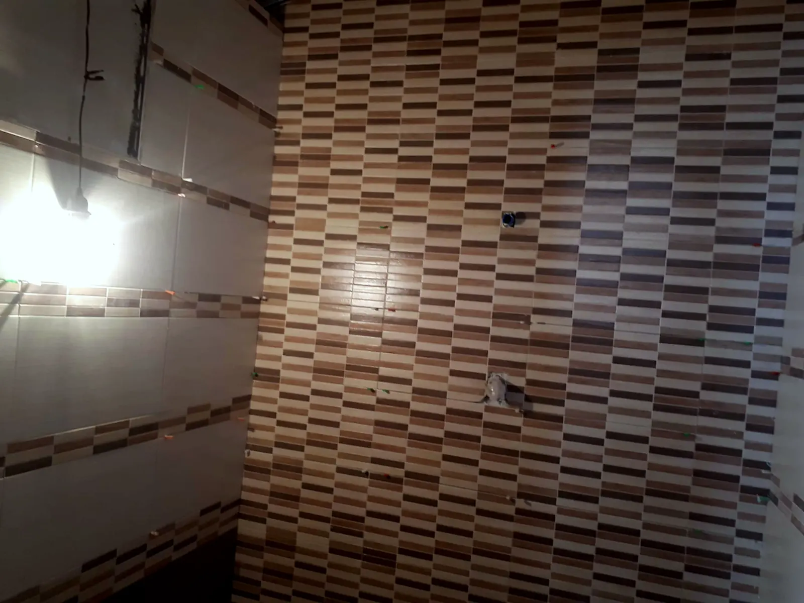 Rivestimento di un bagno con listelli in tre tinte, in fase di posa